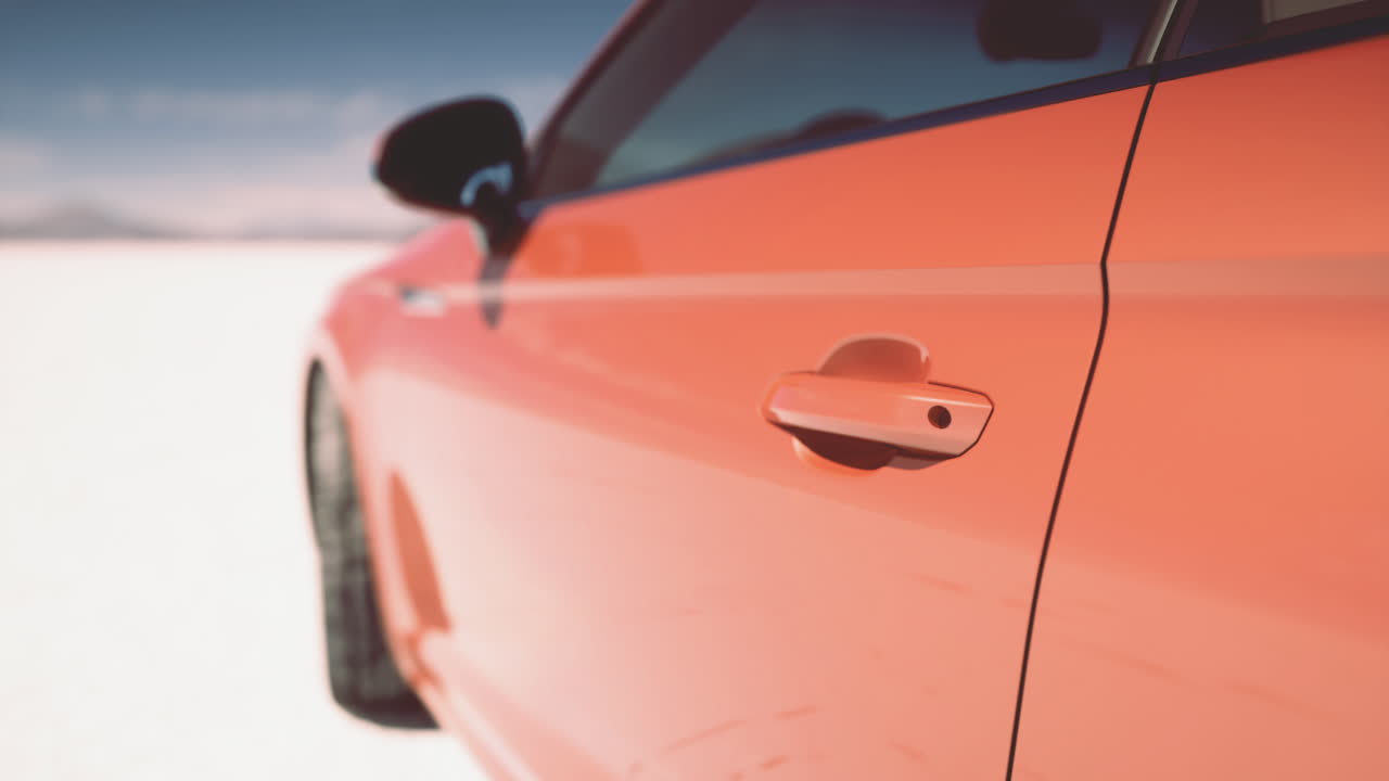 Bright orange car parked on snow covered landscape in the winter sun