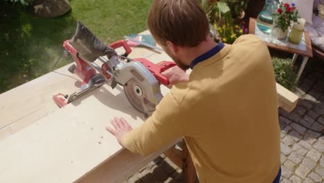 craftsman sawing the wood in the garden