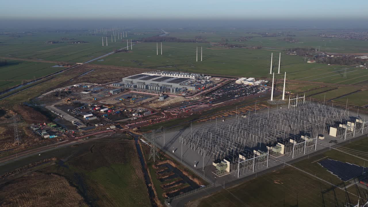 Filmagem aérea com drone de um enorme data center de hiperescala em construção em Westpoort, Groningen, destacando o consumo extremo de eletricidade, a infraestrutura da rede elétrica e a computação em nuvem em larga escala