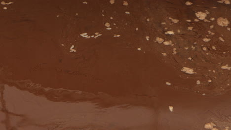 concrete platform at a wastewater treatment plant pans down to reveal brown, swirling sewage water, highlighting industrial machinery and turbulent liquid motion