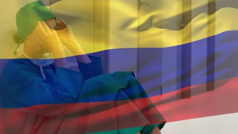 Digital-composition-of-colombia-flag-waving-against-stressed-caucasian-female-surgeon-at-hospital