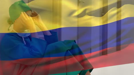 composición digital de la bandera de colombia ondeando contra la estresada cirujana caucásica en el hospital