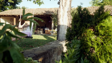 Woman-cradles-cute-cat-sitting-on-garden-swing-under-apple-tree-push-shot