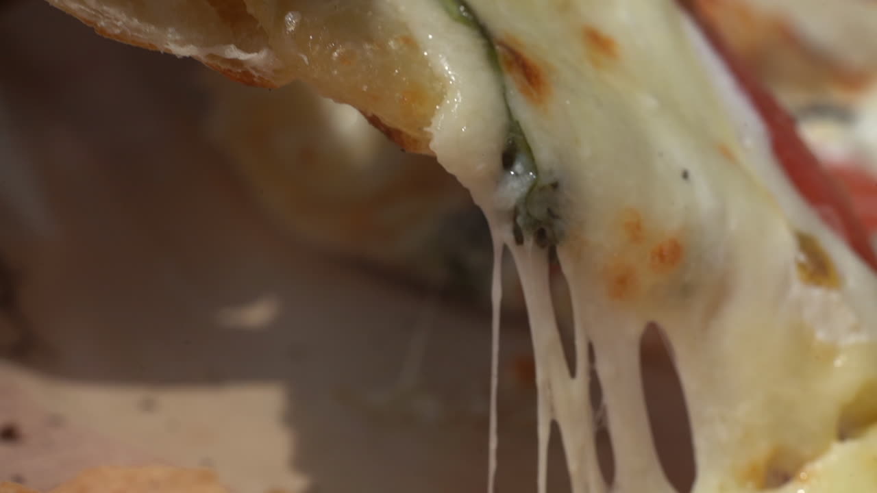recogiendo una rebanada de deliciosa pizza fresca con el queso estirándose mientras se separa - cerrar