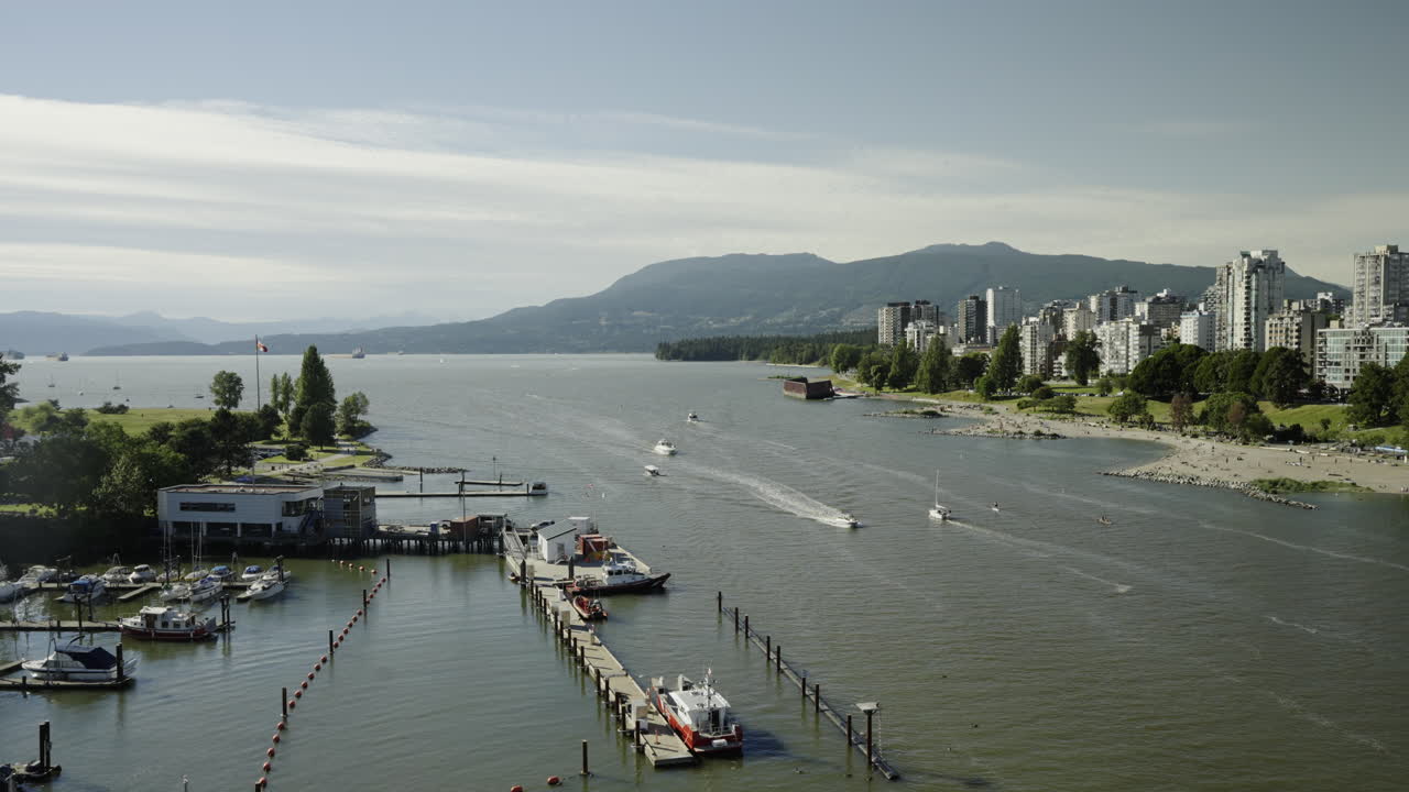 vista panorámica desde el puente burrard sobre la playa del atardecer en vancouver, con barcos pasando y stanley park en la distancia, en cámara lenta