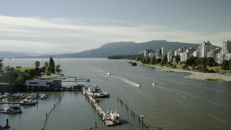 panoramic view from burrard bridge over sunset beach in vancouver, with ships passing and stanley park in the distance, in slow motion