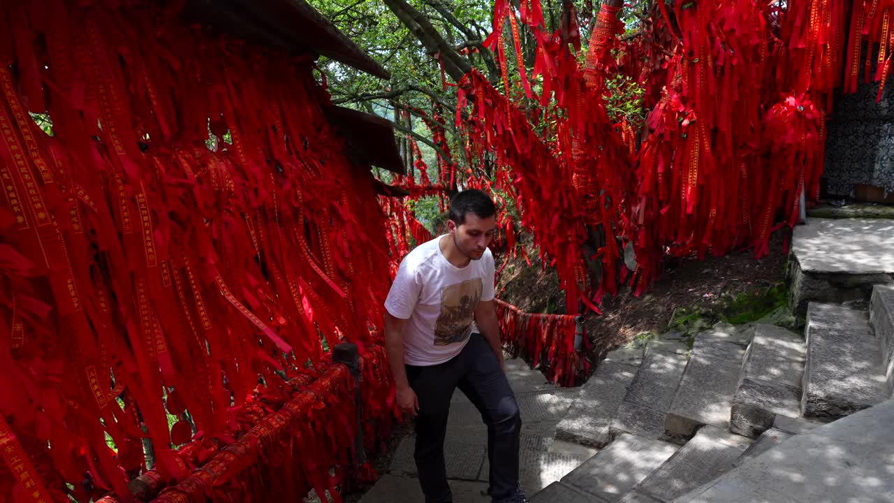 hombre tocando cintas rojas en el área budista de yuanjiajie en zhangjiajie, china
