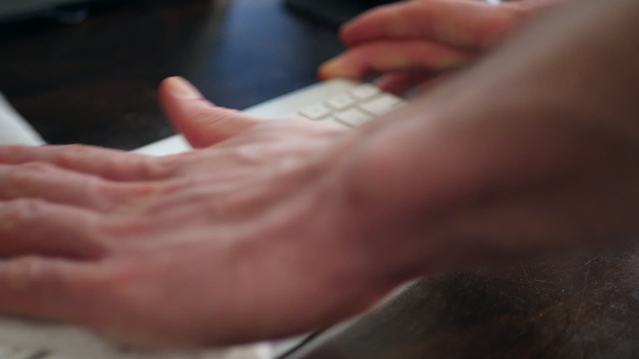 A hand cleaning dust and germs off dirty computer keyboard with an antibacterial sanitizing disinfecting wipe to keep the family home healthy and safe from contagious virus or bacteria