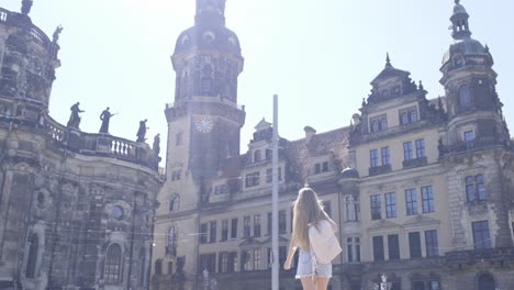 a woman admires the medieval architecture of a historic building in the city, against the backdrop of the vast sky