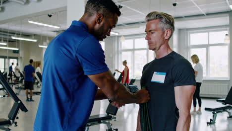 personal trainer assisting client with resistance band exercise