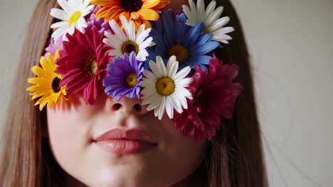woman with eyes covered by a vibrant bouquet of artificial flowers