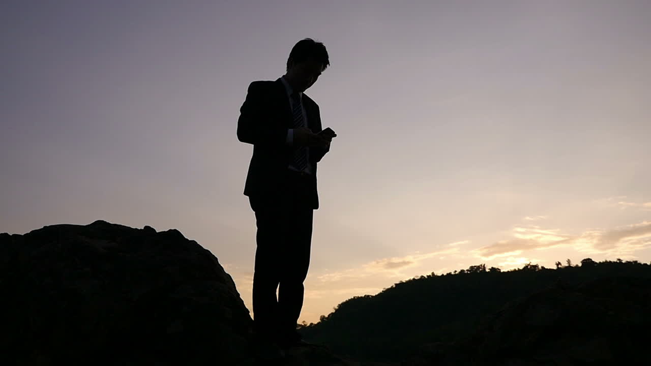 Businessman on a mountaintop at sunset