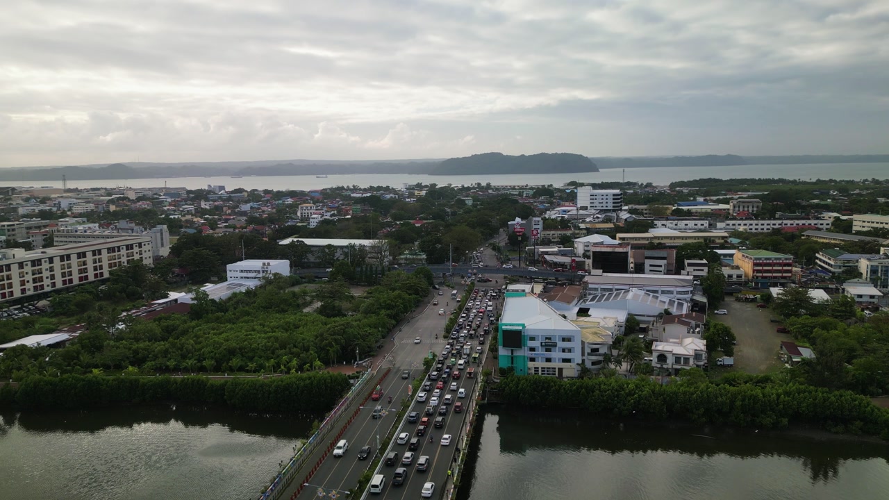 Panoramic aerial view of bridge traffic flow toward coastal urban cityscape during daytime - Iloilo City, Visayas, Philippines