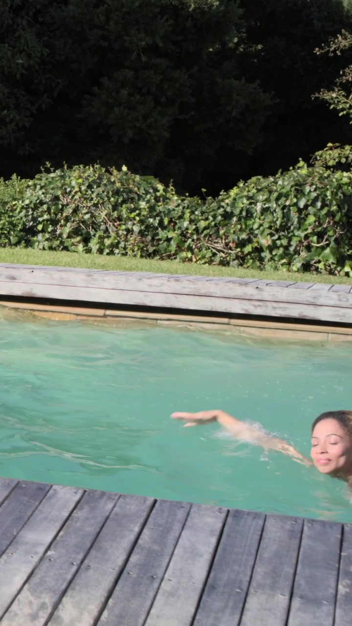 Vertical video: Pushing off, blonde woman in swimwear doing freestyle laps at home pool, splashing