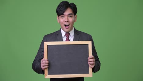 젊은 잘생긴 아시아 사업가 블랙보드를 보여줍니다.