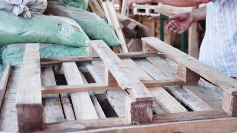 trabajador masculino en una fábrica de madera con una pistola de clavos haciendo una paleta de madera.