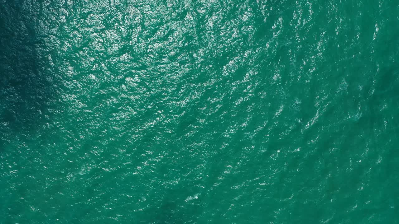 Dark turquoise sea texture of vibrant lagoon water reflecting sunny rays with coral reefs patterns on seabed