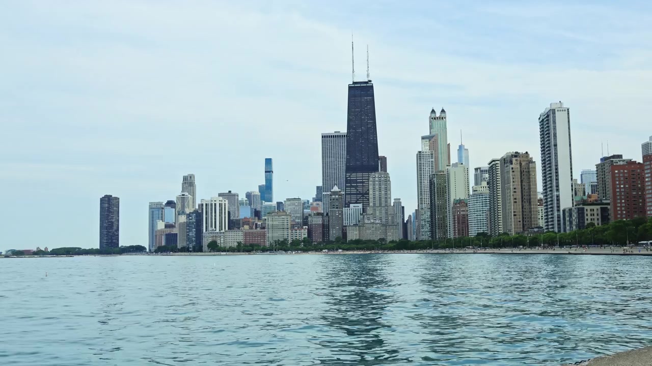 Vista dello skyline di Chicago da Lincoln Park vicino al Lago Michigan in una giornata estiva serena, con vari grattacieli e acqua calma in primo piano.