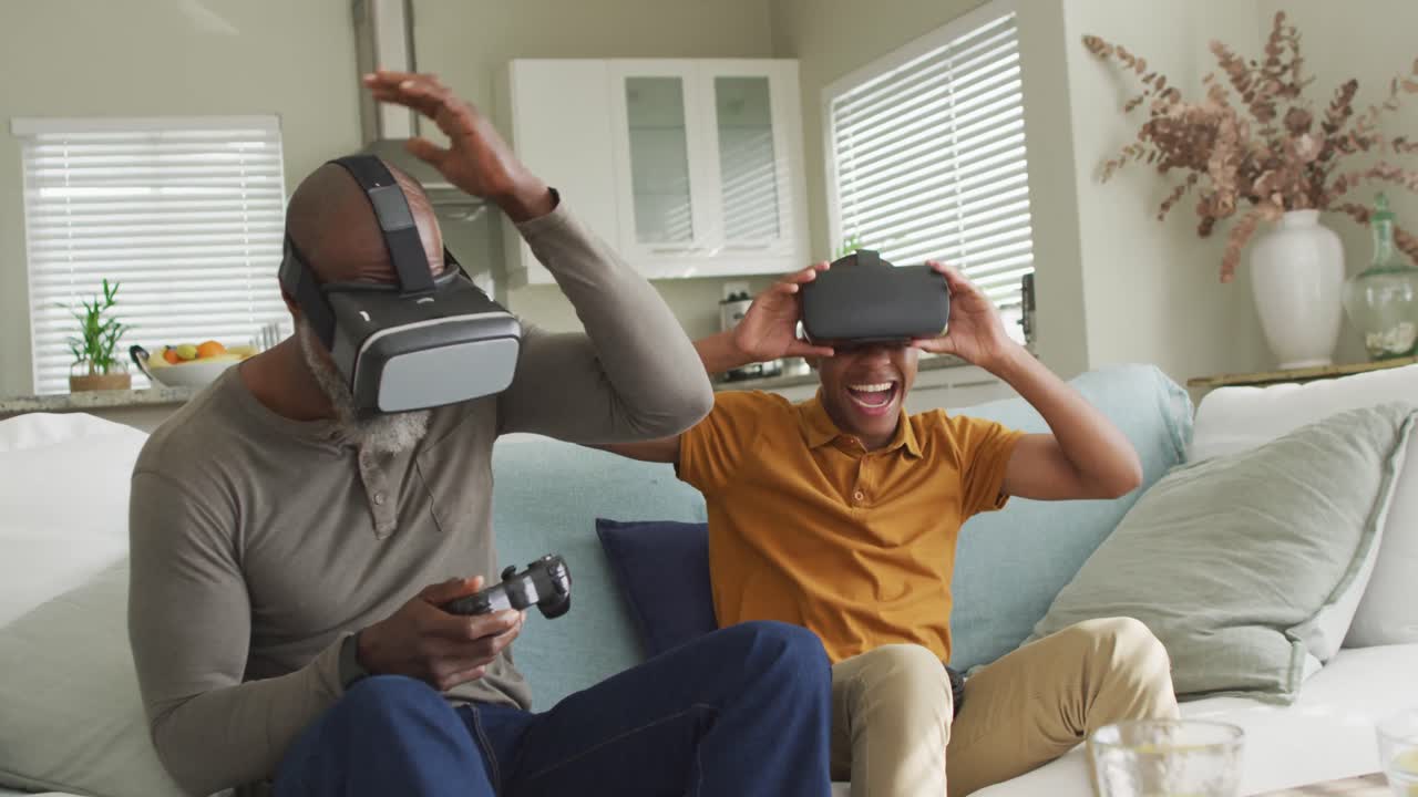 Video di un felice padre afroamericano e suo figlio che indossano visori VR e giocano ai videogiochi.