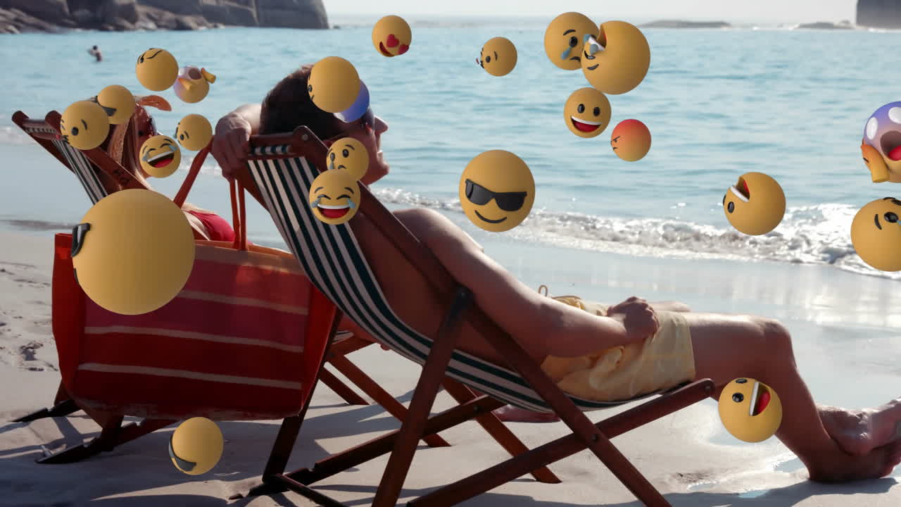 Man relaxing on beach with floating emoji animation over ocean background