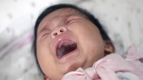 crying baby girl expressing hunger and frustration while lying on the bed. a relatable moment for parents, highlighting infant communication and early childhood needs, ideal for parenting themes.