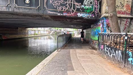 person running under graffiti-covered bridge