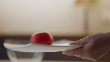 woman puts ripe red tomatoes on square plate in kitchen