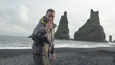 Slow-motion-shot-of-a-tourist-making-gestures-at-Reynisdrangar-Rock-Formation