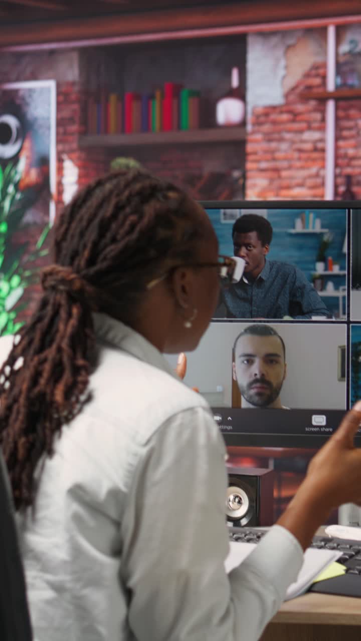 Vertical video Manager greeting employees during videocall from home, looking over paperwork