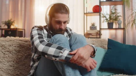 young man sad at home with headphones melancholic music track tearful mood quiet heartbreak moment