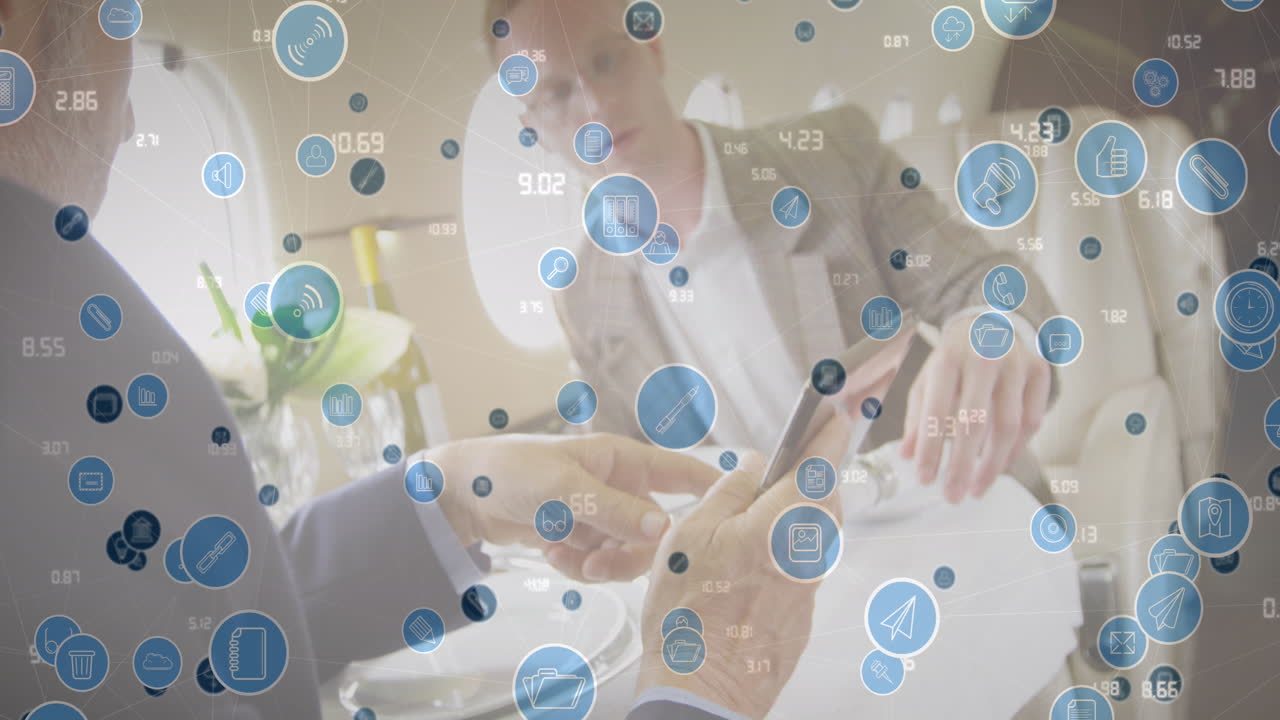 Animation of icons and numbers over caucasian entrepreneurs discussing reports in restaurant