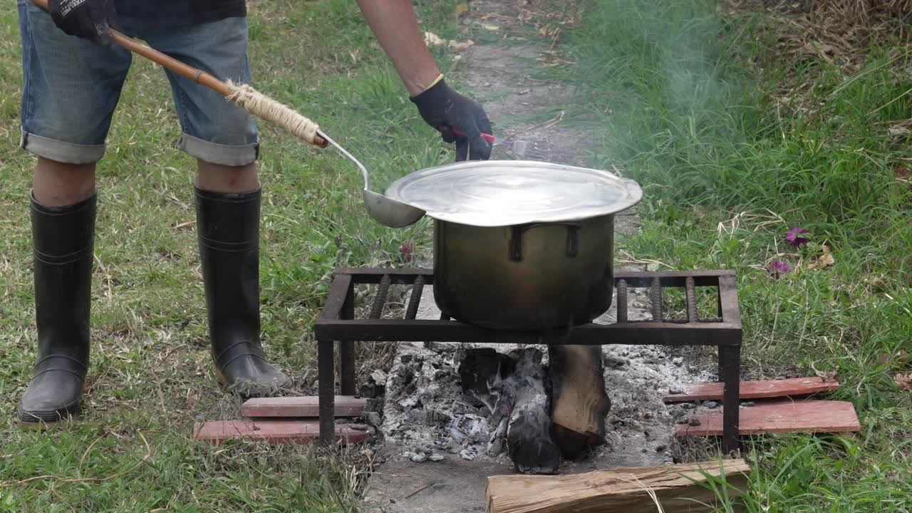 Open wood fire cooking outdoor camping stove, big pot of food simmer over high heat