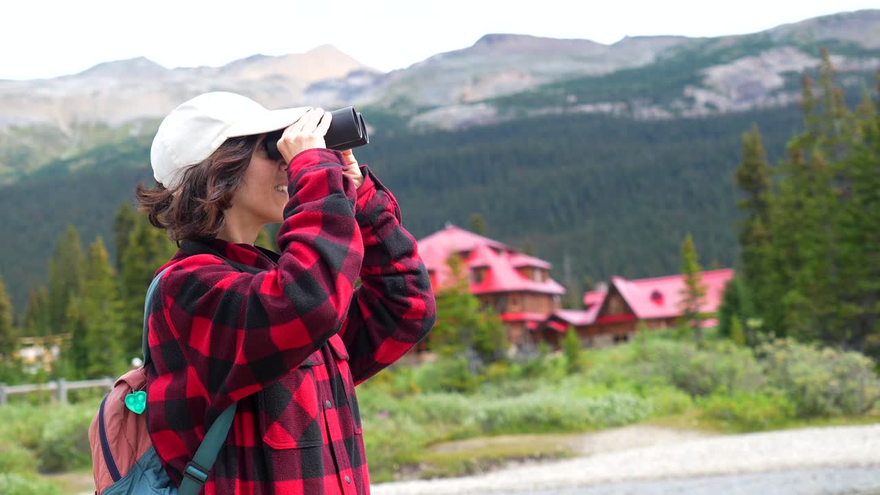 Donna con binocolo che ammira il panorama montano