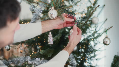 un niño y su padre cuelgan bolas de navidad en el árbol de navidad.