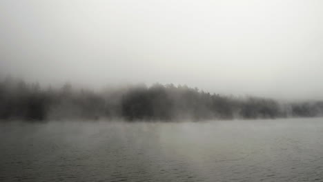 drone shot low over the water level of the foggy sea, on a dark overcast day