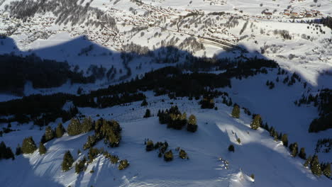 aerial view tilting down over a mountain valley to see avalanche barriers and mountain top in the sun in the french alps in winter