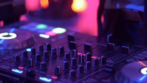 knobs and sliders being adjusted on dj on turntable mixer with warm lighting, filmed as close up