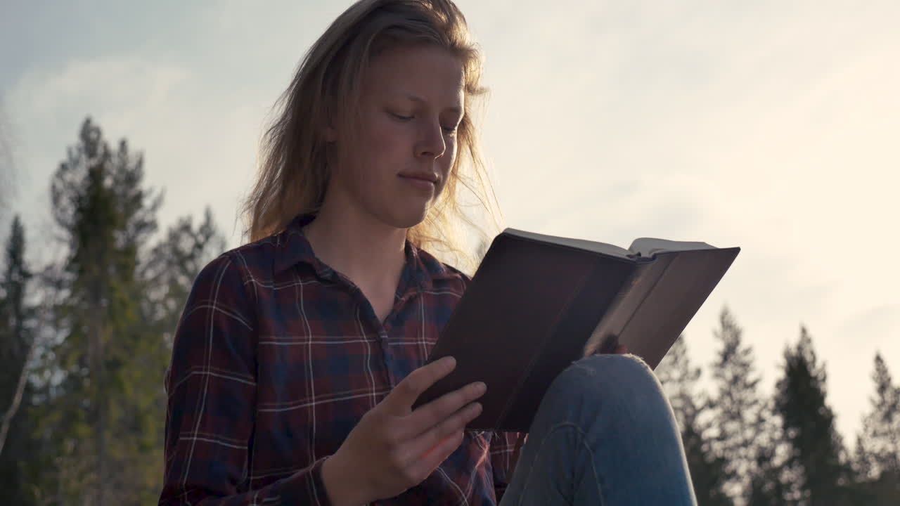 Fille lisant la Bible dans la forêt par une journée ensoleillée
