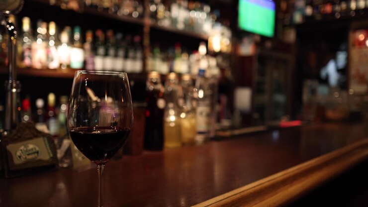 Primo piano di un bicchiere di vino con un bar sullo sfondo