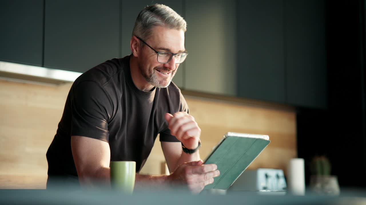 Smiling Man Browsing Digital Tablet in Modern Kitchen