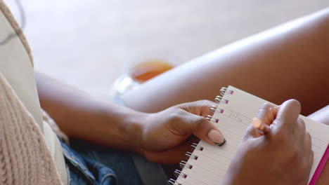 writing in notepad, woman journaling while relaxing at home with tea