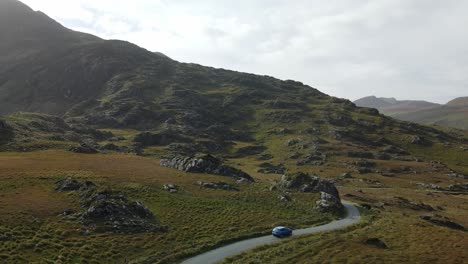 un coche viaja por la estrecha y sinuosa carretera de irlanda en otoño