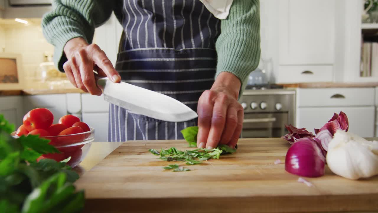 Midsection of senior caucasian woman standing in kitchen and preparing dinner