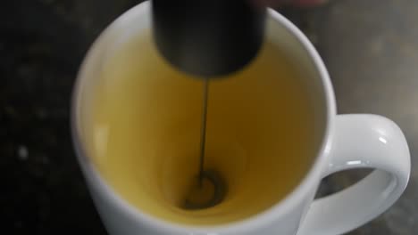 Close-up-shot-of-motion-while-mixing-orange-juice-from-orange-powder-with-a-mixer-in-twister-shape-in-a-white-cup