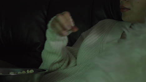 female sitting on a sofa and eating popcorn - close up