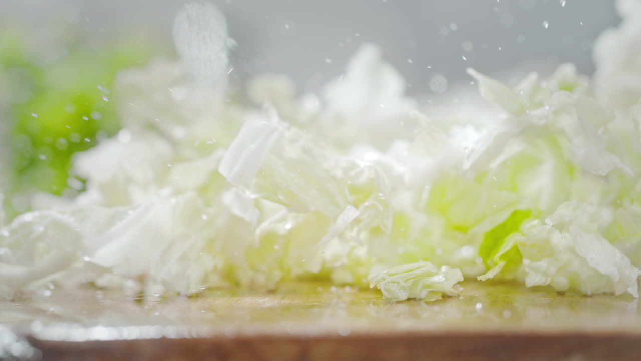 개진 중국고추 잎이 은 나무 테이블에 떨어지고, 거시 및 느린 동작으로 물방울이 아집니다.