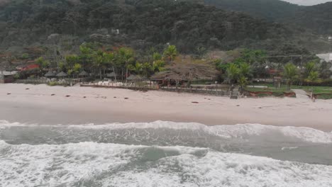 Drone-footage-of-the-beach-above-the-sea,-mountain-in-front-of-the-sea,-cloudy-day,-waves,-landscape-of-Juquehy,-Ubatuba,-northern-coast-of-São-Paulo,-Brazil