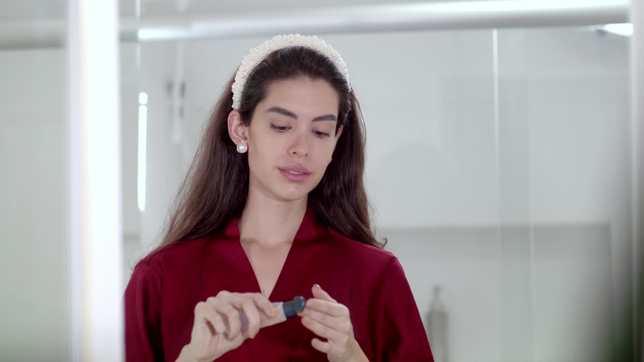 una mujer joven usa cuidadosamente un suero hidratante para rehidratar su piel.