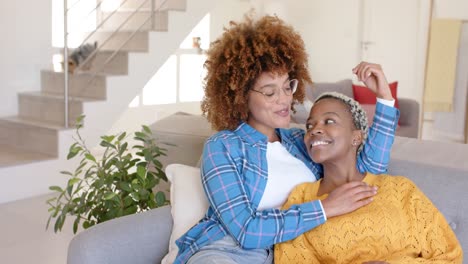 Happy-diverse-female-lesbian-couple-talking-and-embracing-with-dog-in-background-in-slow-motion