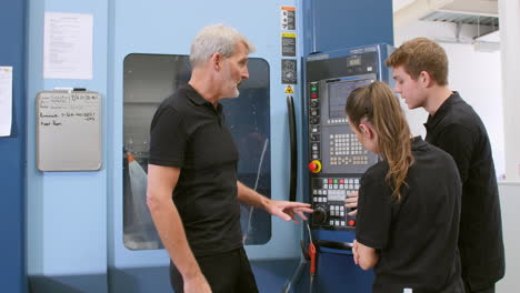 two apprentices working with engineer on cnc machinery